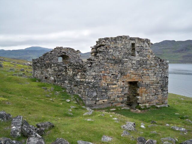 Stone ruins of the medieval Norse Hvalsey Church overlooking a fjord in South Greenland